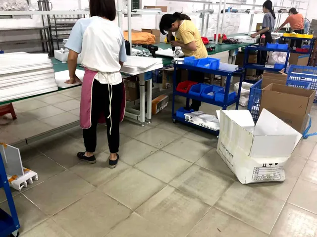 Workers preparing cabinet panels and parts at assembly benches